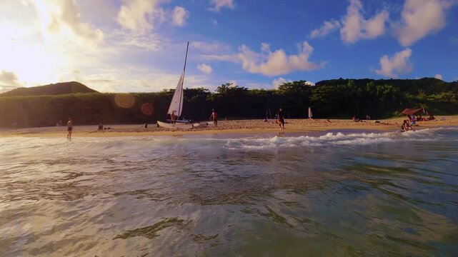 still view from the ocean sea shallow water with wave pounding onto the shore look out to the beach side with kite surfing boat surf board and people walking lying sitting on the beach at good weather