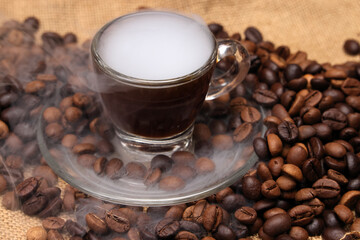 Dark brown Coffee bean macro closeup flow move fall drop pan roll smoking roasting cooking transparent clear glass cup saucer pour liquid on jute fabric background