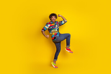 Full size photo of pretty young guy winning raise fists wear trendy colorful outfit isolated on yellow color background