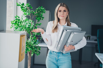 Photo of young corporate woman pile stack folders shrug shoulders modern office business center...
