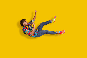 Full length photo of handsome young male frightened falling down dressed stylish colorful garment isolated on yellow color background