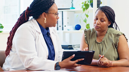 Doctor Consulting With Patient Using Digital Tablet in Medical Office Environment for Health Evaluation