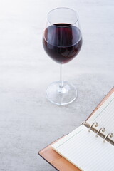 赤ワインを飲みながら、リング式のシステム手帳に日記をつけているイメージ写真
