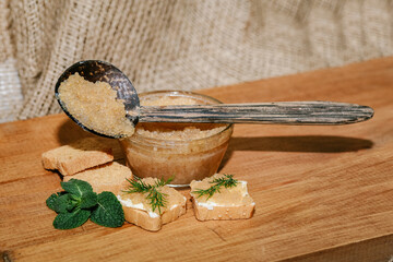 Pike caviar on a wooden spoon on a wooden background with mini sandwiches close-up with copy space