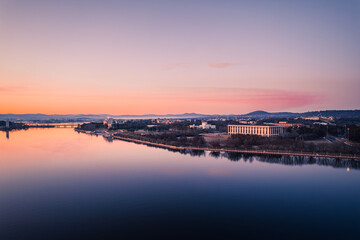 Scenic view of river by buildings against sky during sunset