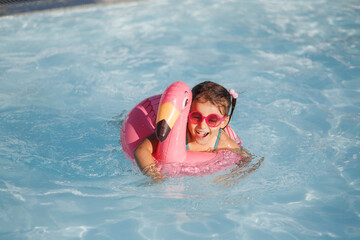 Cute funny toddler girl in a sunglasses relaxing on inflatable toy ring floating in pool have fun...
