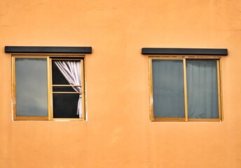 Two windows with curtains on them. One window is open. The other window is closed