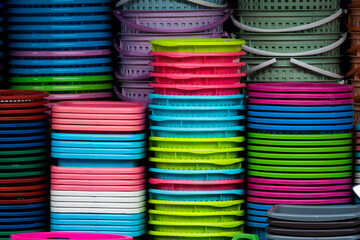 A pile of colorful plastic containers, including green, pink, and blue. The containers are stacked on top of each other, creating a colorful and vibrant display