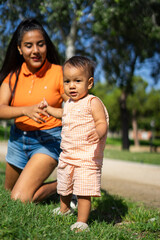 1 year old latin baby girl standing with her young mother outdoors. Peruvian family