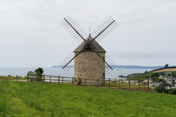 Le moulin de Luzéoc sur la presqu'île de Crozon, enveloppé de verdure, se distingue avec la mer d'Iroise en toile de fond.