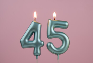 Burning blue birthday candles on pink background, number 45