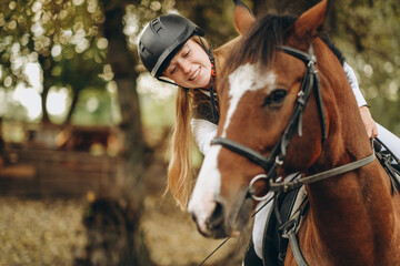 Obraz premium A young woman jockey lies on her horse and hugs her.