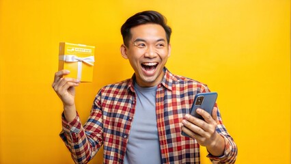 Excited happy young indonesian man winner feeling joy using smartphone winning lottery game, betting, getting cashback online gift in mobile app message holding cell phone isolated on yellow backgroun