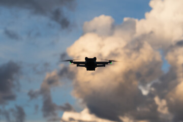 Silhouette of a mini drone in flight against a sky with thunderclouds.