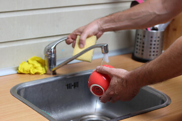 Man washing dishes in the kitchen. Close-up of hands.