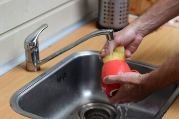 Close up photo of male hands doing dishes. Running water, dishes in sink. Water saving concept. 