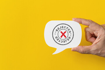 Hand hold real white speech bubble paper cut with grunge rejected stamp on yellow background