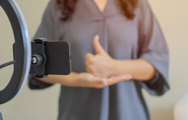 Shot of woman talking and showing sign language while recording video blog for deaf people.