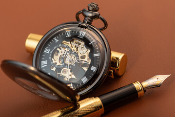 Fountain pen, beautiful fountain pen and beautiful vintage watch positioned on leather surface, selective focus.
