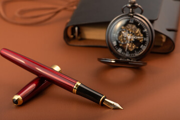 Fountain pen, beautiful fountain pen and beautiful vintage watch positioned on leather surface, selective focus.