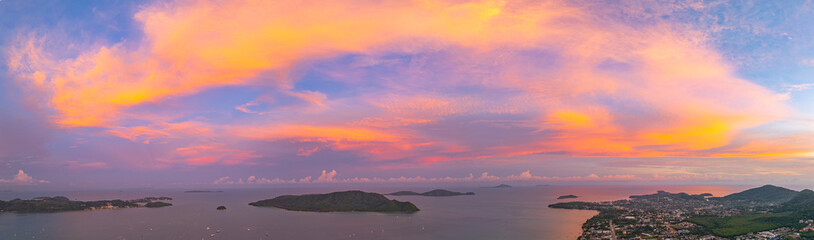 Obraz premium A breathtaking aerial view of a vivid sunset over the hills of Phuket. Phuket big Buddha on the hill top. The sky is painted with deep oranges, reds, and purples as the last light of the day
