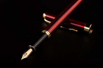 Naklejka premium Fountain pen, beautiful red and gold fountain pen, positioned on dark background, selective focus.