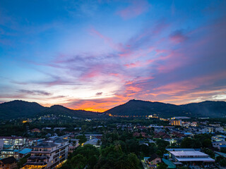 An enchanting aerial view of Phuket city at twilight, with vibrant city lights illuminating the streets. The soft hues of the sky blend seamlessly with the distant horizon, creating a serene