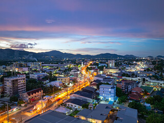 An enchanting aerial view of Phuket city at twilight, with vibrant city lights illuminating the...