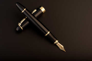 Fountain pen, beautiful black and gold fountain pen, positioned on dark background, selective focus.