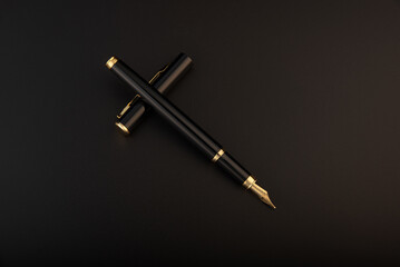 Fountain pen, beautiful black and gold fountain pen, positioned on dark background, selective focus.