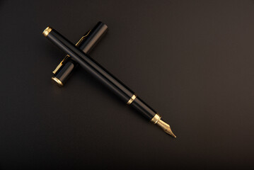 Fountain pen, beautiful black and gold fountain pen, positioned on dark background, selective focus.