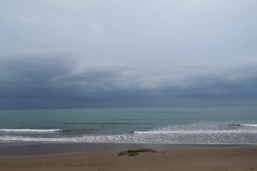A stormy beach scene with crashing waves and dark clouds over the sea