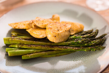 Fried chicken breast pieces with asparagus on plate