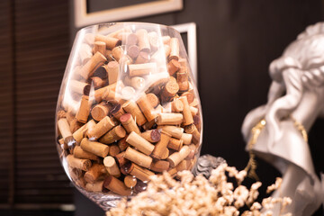 Close-up of several used wine corks in a large glass