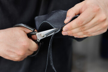 Replacing the cover on the steering wheel of car. Master cuts out details from leather with scissors