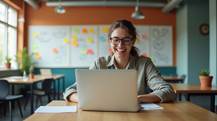Focused Young Woman Working on Laptop in Modern, Collaborative Office Environment