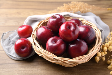 Red plum fruit in basket on wooden background