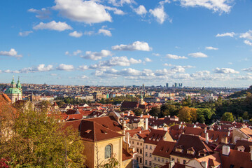 Fototapeta premium Scenic Aerial View of Prague With Red Rooftops and Blue Sky. Beautiful aerial view showcasing the iconic red rooftops of Prague under a vibrant blue sky with fluffy clouds.
