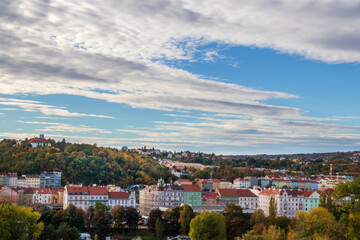 Fototapeta premium panoramic view of Prague on a sunny autumn day, colorful houses with red roofs and yellow-green trees