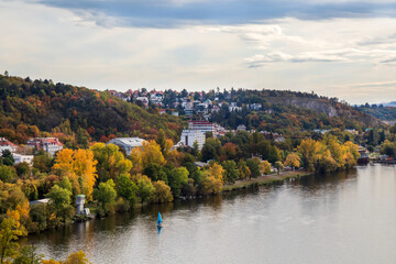Fototapeta premium view of autumn Prague, green and orange trees and red roofs of houses, Prague in October
