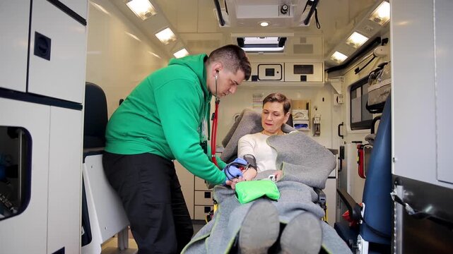 Emergency medical technician taking care for an injured woman inside ambulance car. Healthcare paramedic EMS worker