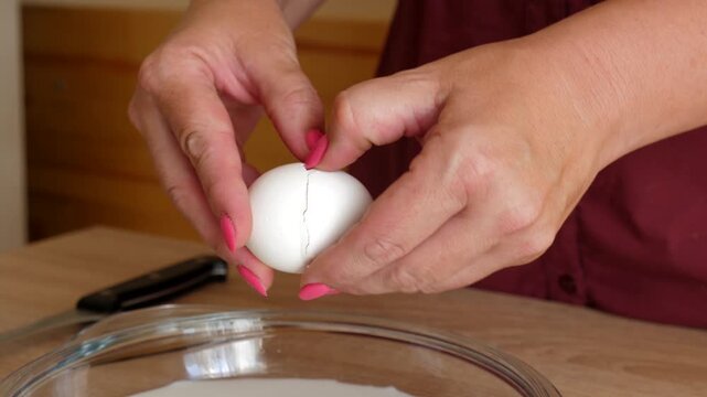 The egg is broken with a knife and poured into a plate.