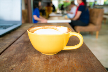 Hot latte art coffee with laptop on wooden table