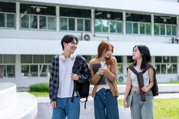 Obraz premium Three young people are walking down a sidewalk, smiling and carrying backpacks