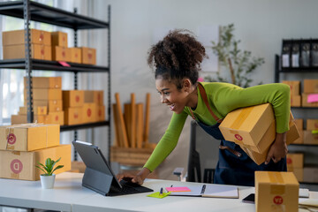 A woman in a green shirt is standing in front of a table with a laptop and boxes