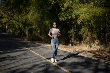 Fototapeta premium A woman is running on a road with trees in the background
