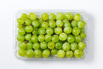 A top view of fresh green grapes neatly packed in a clear plastic container, placed against a white background