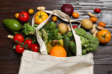Vegan food delivery. Bag with different fresh vegetables, nuts and fruits on wooden table, flat lay