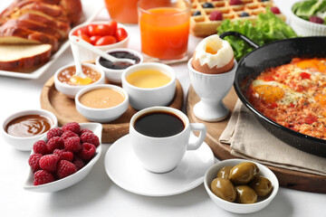 Cup of coffee and different meals served for breakfast on white table
