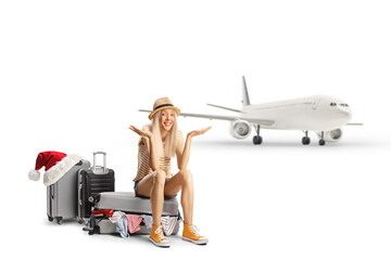 Female toursit sitting on a suitcase full of clothes and waiting for a christmas flight